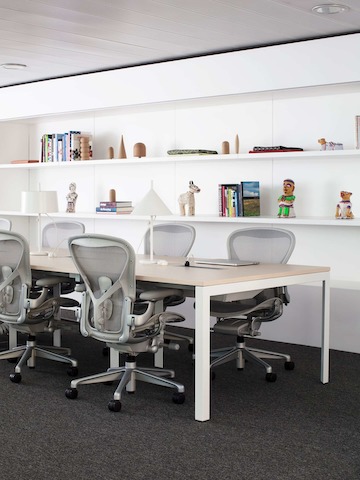 Five grey Aeron Chairs surround a work table in the Milan showroom.