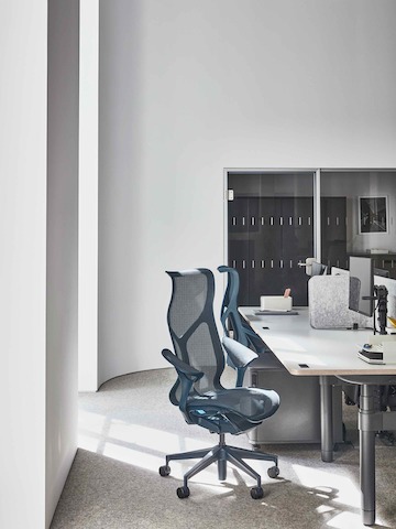 Workspace within the Paris showroom, with blue high back Cosm chairs around an Atlas desk.