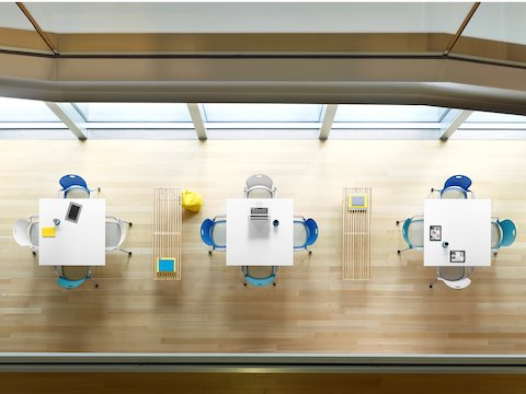 Overhead view of white and blue Caper Stacking Chairs around square tables in a collaboration space.