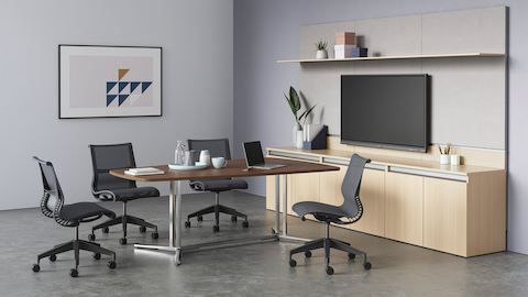 A dark wood video oval Everywhere Table arranged in a video conference environment, surrounded by four Setu Chairs.