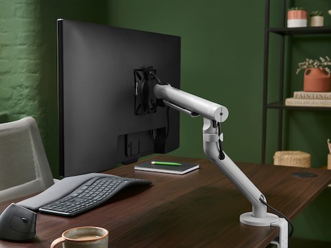 Silver Flo Single monitor arm viewed from the side in an office set up.