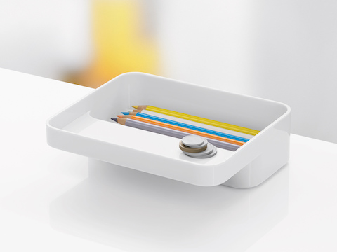 The small version of a white Formwork Tray, with pencils in the rear compartment and coins on the cantilevered ledge.
