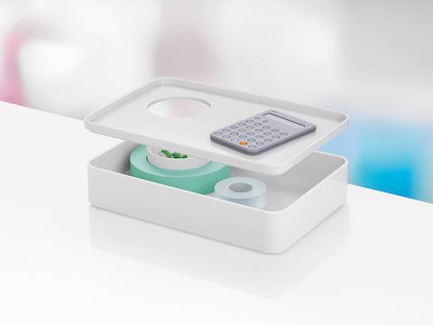 A small white Formwork Box with the removable lid hovering above the storage compartment and enclosed cup.