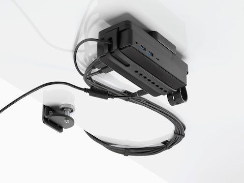 Loop Micro Mount attached under a desk cradling a thin client or power docking station with attached cables that are routed tidily to the edge and above the desk.