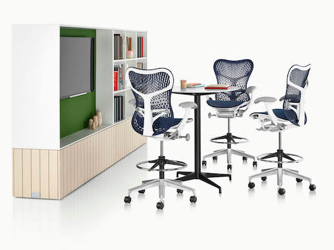 Three blue Mirra 2 Stools surround a round Eames Table in a casual collaboration area.