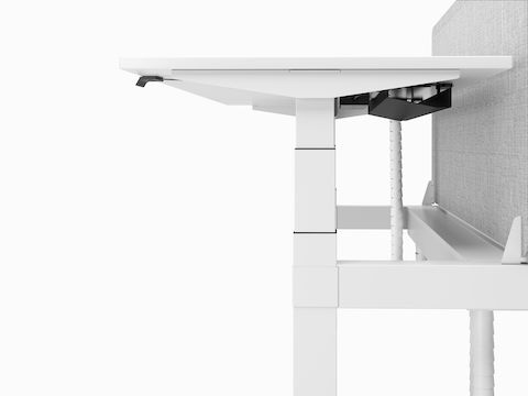 A close-up profile view of a white Nevi Link desk and grey screen showing the T-shaped leg and cable tray under the work surface.