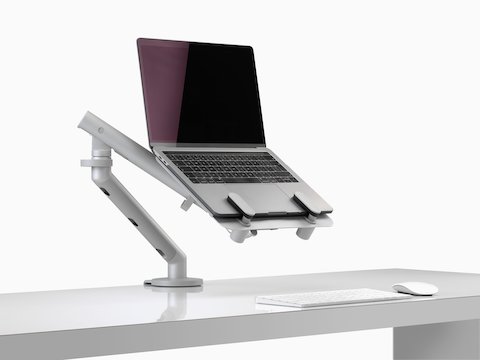 An open laptop raised to eye level and supported by an Ollin Laptop Mount and Flo Monitor Arm.