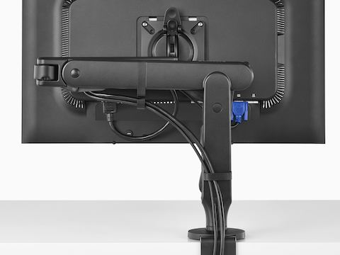 A monitor attached to a black Ollin Monitor Arm, viewed from behind and showing the cable management system.