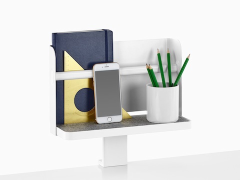 A Ubi Attached Shelf with a backdrop supports a book, smartphone, and pencil cup.