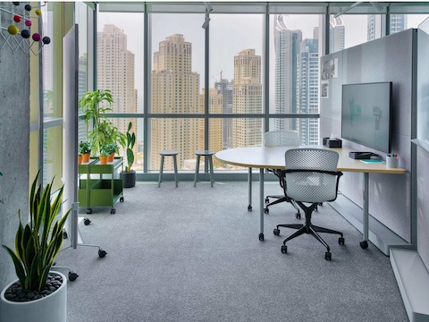 OE1 white Huddle Table with two Keyn Chairs, OE1 agile wall, OE1 Mobile Easel and OE1 Storage Trolleys and Revolver Stools in the background.