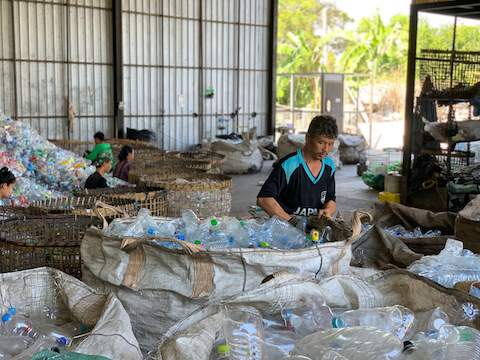 A man sorting plastic bottles in a warehouse.