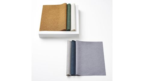 Two stacks of 100% recycled content fabric swatches in textured, neutral colors.