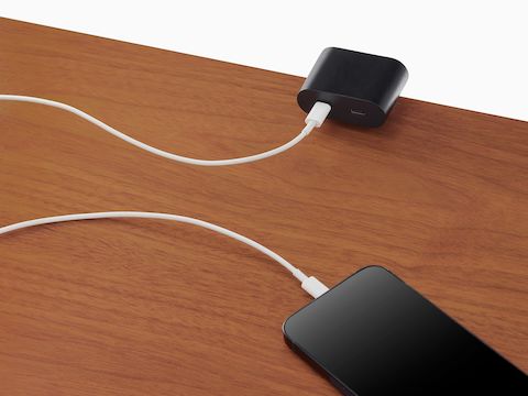 Ello Mini surface clamp USB-C power solution shown in black charging a phone.