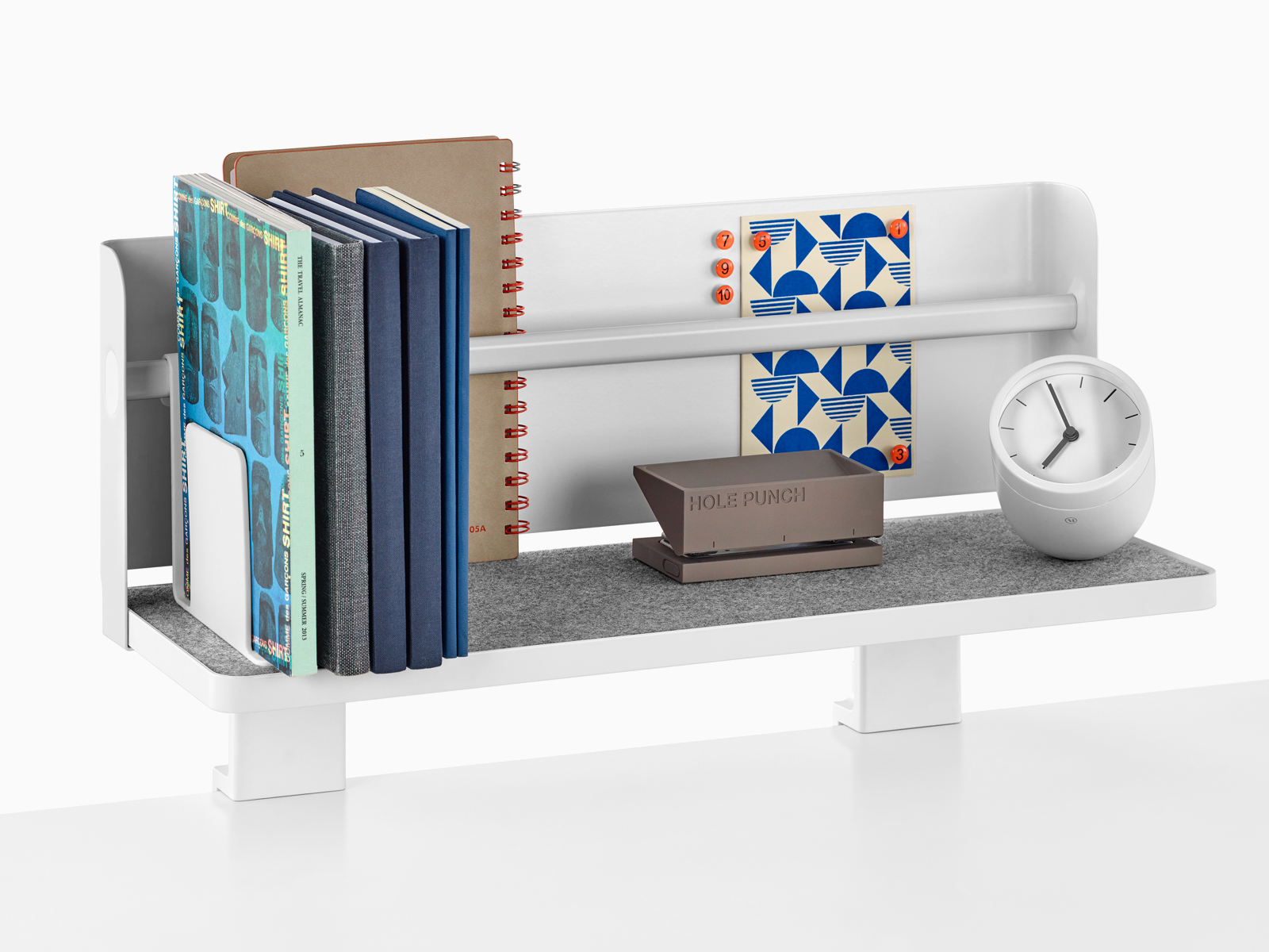 A Ubi Attached Shelf with a backdrop supports a small clock, hole punch, books, and other reference materials.