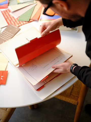 Flipping through a red folder with documents inside.