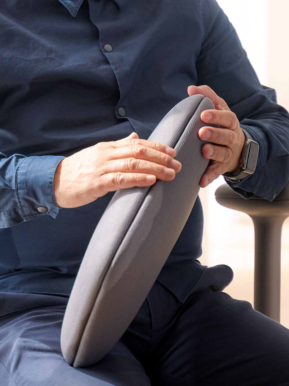 Designer Naoto Fukasawa sitting in an Asari high-back chair in cocoa.