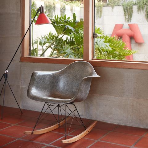 A grey vintage Eames fibreglass armchair on rocker base in the corner of Steve Cabella's living room.