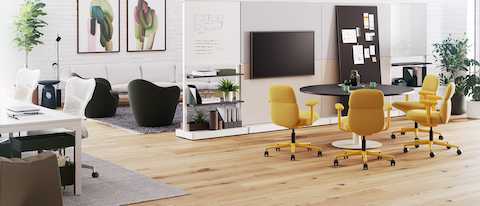 Four mid back Asari chairs in yellow surround a round table in an open-plan meeting space.
