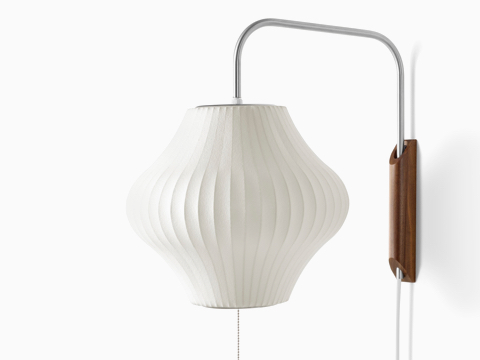 A Nelson Pear Wall Sconce with a swivel arm and walnut wall mount.