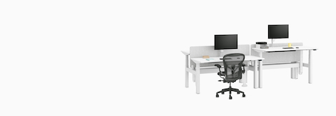 Nevi Link Sit-Stand four-desk configuration in white with grey fabric screens and two desks raised to standing height, Lima Monitor Arms and an Aeron Chair.