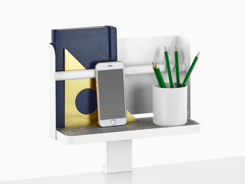 A Ubi Attached Shelf with a backdrop supports a book, smartphone, and pencil cup.