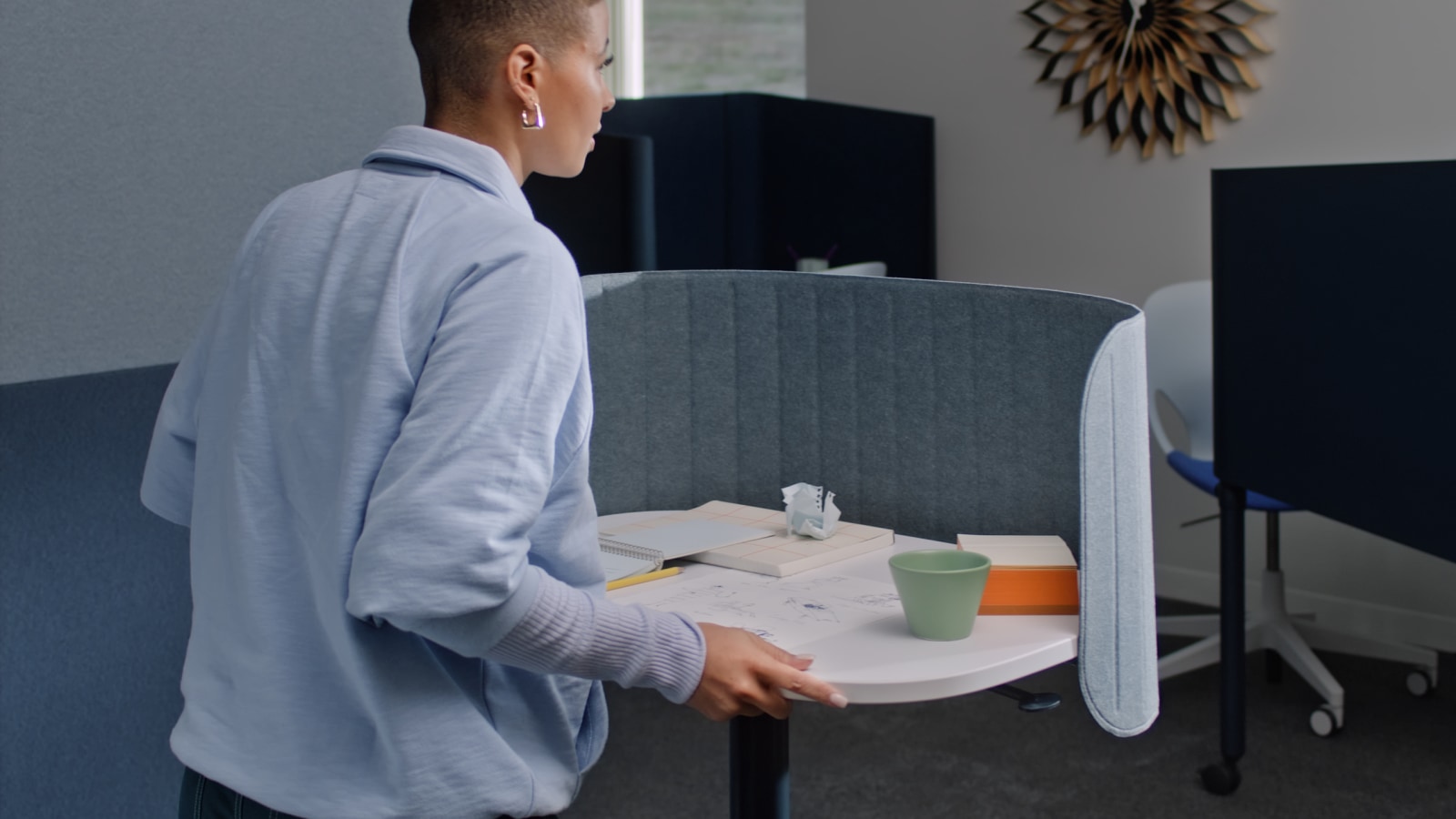 A video showing a woman adjusting the height of a Passport Work Table and rolling it to a different location.