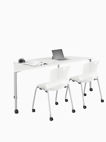 White trapezoid Everywhere Table with a pair of white Caper stacking chairs. Select to go to the Everywhere Tables product page.