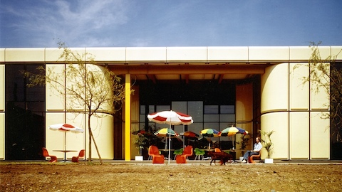 A man sits outside Herman Miller's manufacturing plant in Bath, England. Select to go to an article about Max De Pree's design brief for the building.