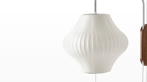 Close view of a Nelson Pear Wall Sconce with a swivel arm and walnut wall mount.