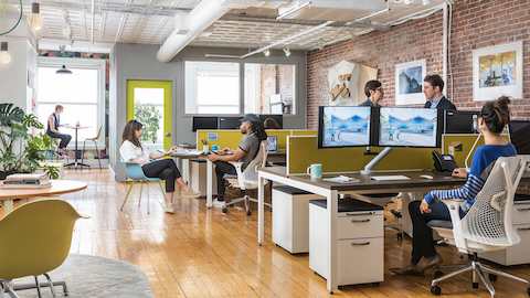 People working and collaborating at their desks in an open office setting.